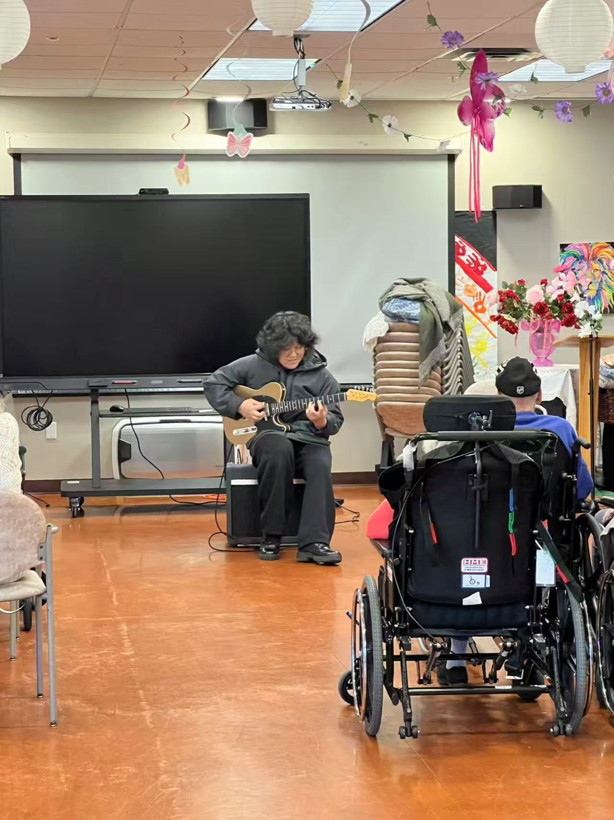A senior resident playing an electric guitar at the community room