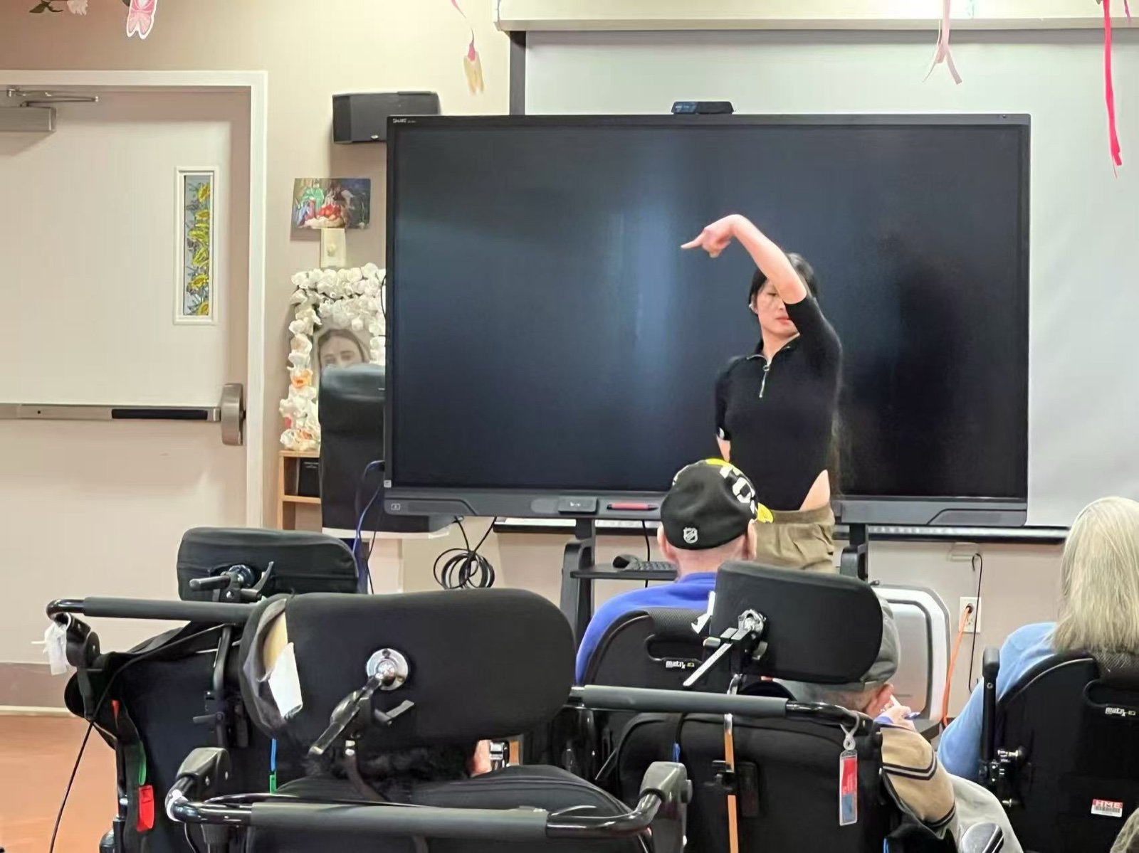 A volunteer giving a dance performance on the activity-room stage as residents look on