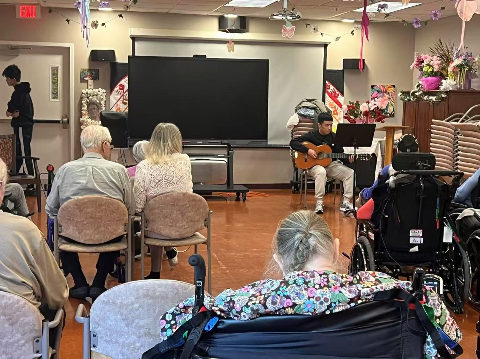 A student volunteer playing acoustic guitar with quiet focus